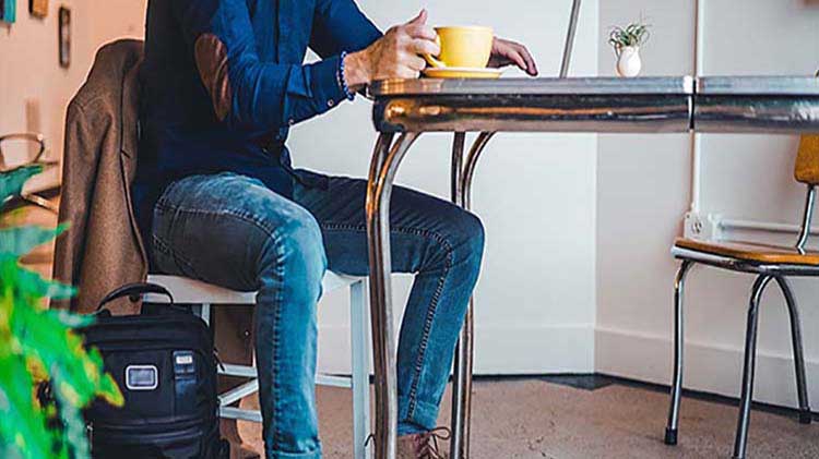 Man researching being a landlord and managing rental properties on laptop while drinking coffee.
