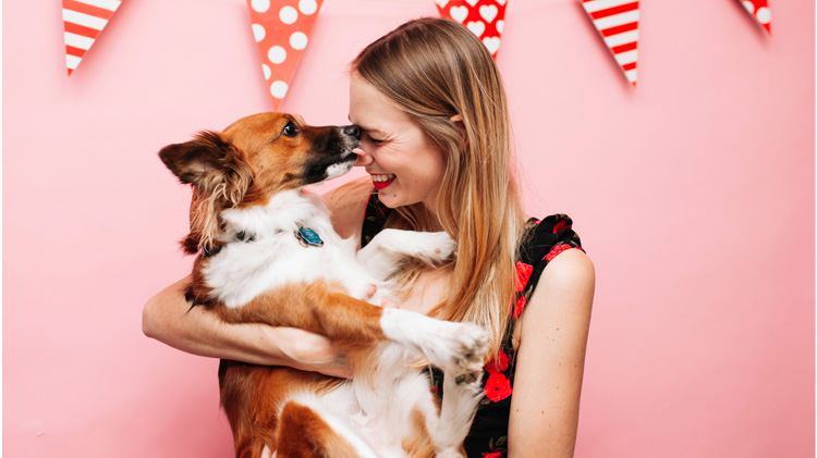 Woman holding and getting kisses from her dog valentine.