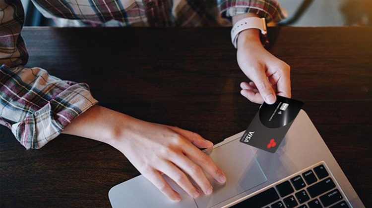 Person using their laptop while making an online purchase with a credit card.