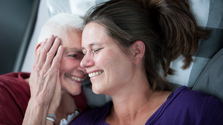 An older mother and adult daughter emotionally embracing.