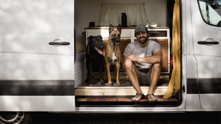 Smiling man sitting with his dogs in a motorhome