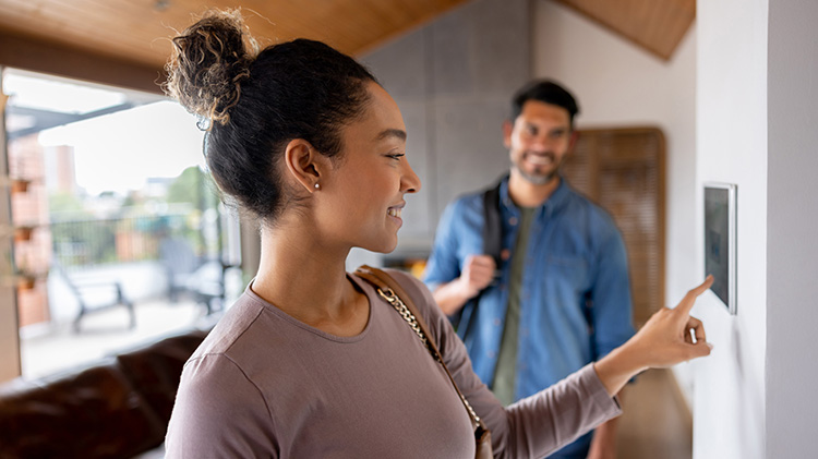 Couple leaving their house and setting the alarm using a home automated system