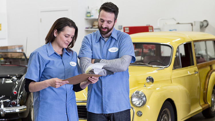 A woman and man, who are car mechanics, are reviewing a valuation in a classic car shop.