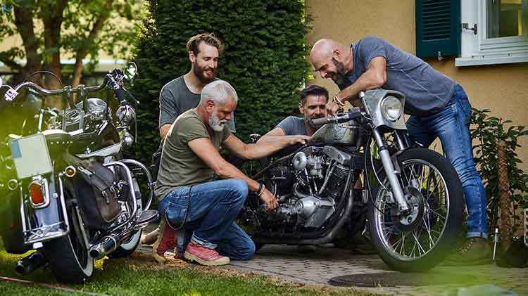 Four friends with motorcycles outside house