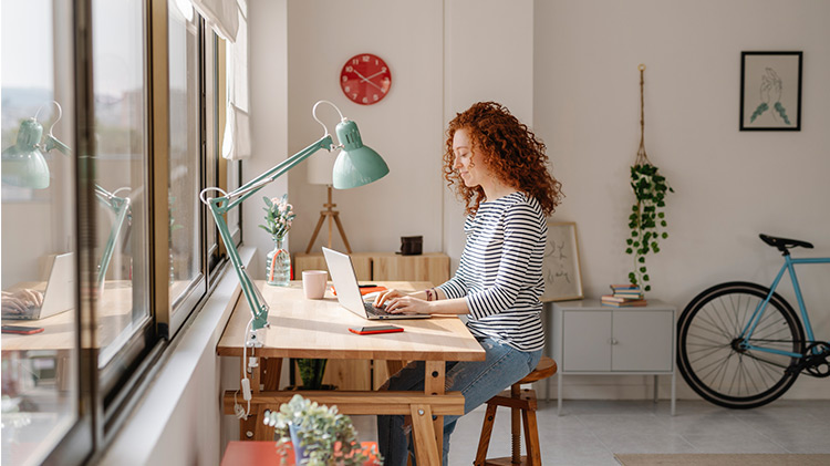 Woman sitting at computer reviewing insurance information in her apartment.