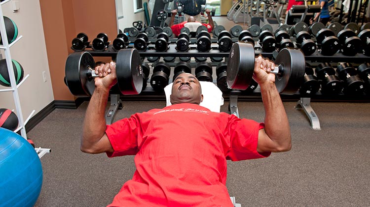 Using his company perks, a man lifts weights at the gym.