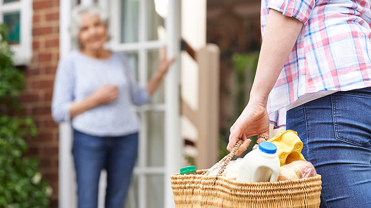 Carrying a basket of items to an elderly neighbor.