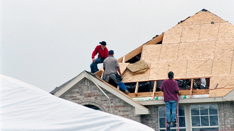 Contractors replacing a roof after storm damage.