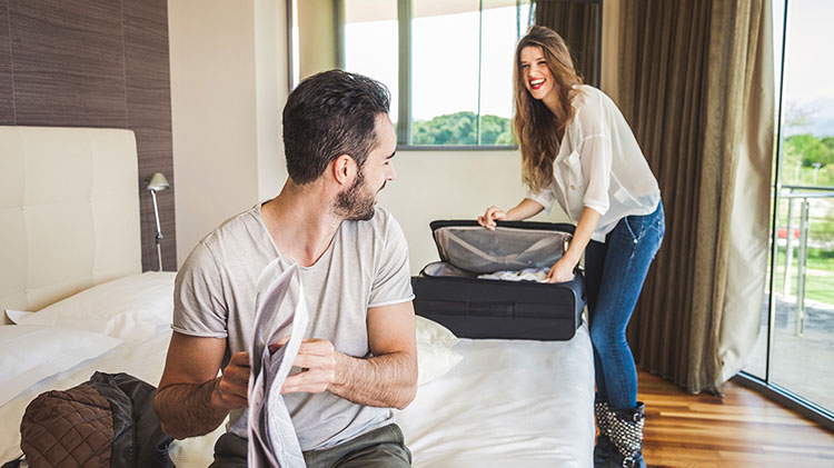 Una pareja desempacando para una estancia en un hotel.