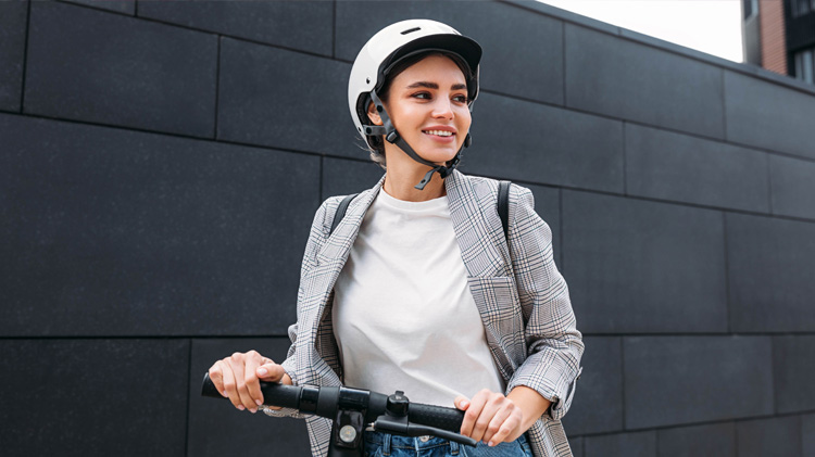 A woman wearing a helmet riding a scooter from an electric scooter rental.