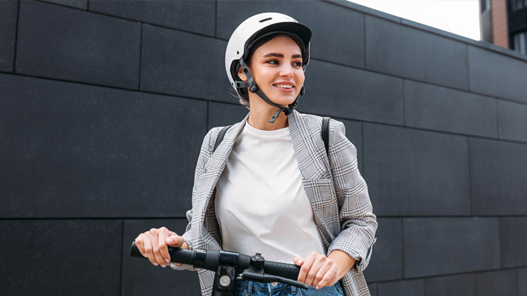 A woman wearing a helmet riding a scooter from an electric scooter rental. 