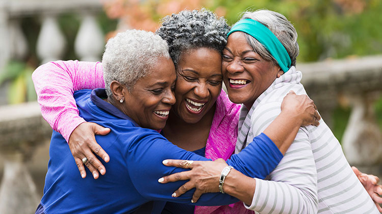 Three women hug and laugh as they enjoy their retirement
