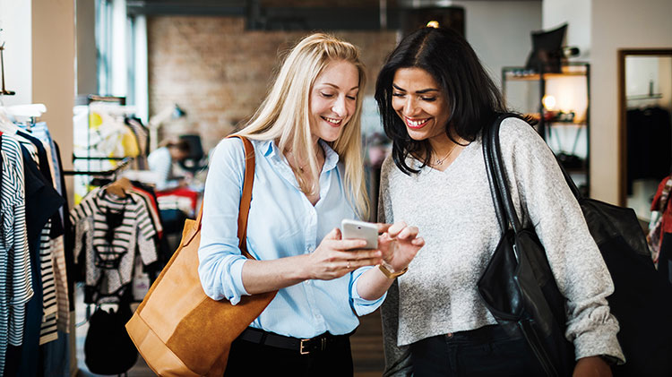 Woman showing her friend how to organize her phone apps in folders