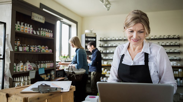 Business owner reviewing types of insurance for small business on her laptop.