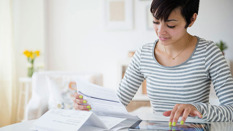 Woman sitting at table figuring out how to build a savings account.