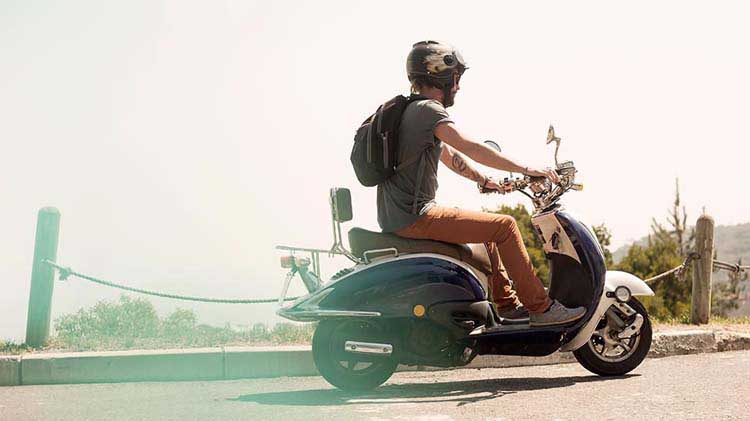 Man in helmet riding a scooter.