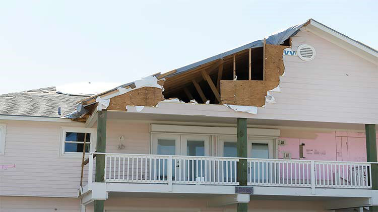House with part of roof missing from hurricane damage.