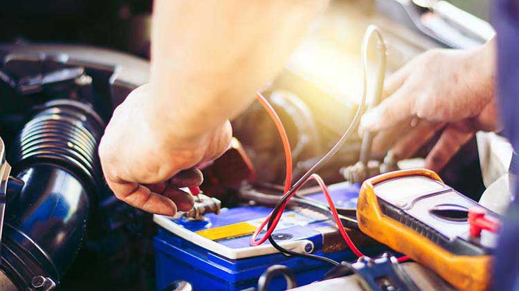 A man is using a meter to test a car battery.