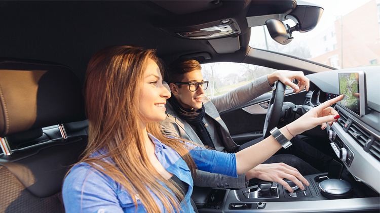 Driver using one of his car features, the onboard navigation system.