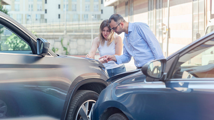 Man and woman going over insurance information after a car crash.