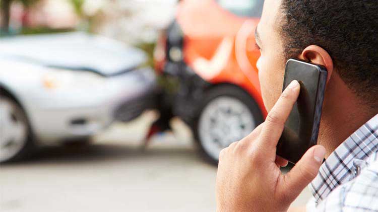 Man on cell phone looking at a car accident.
