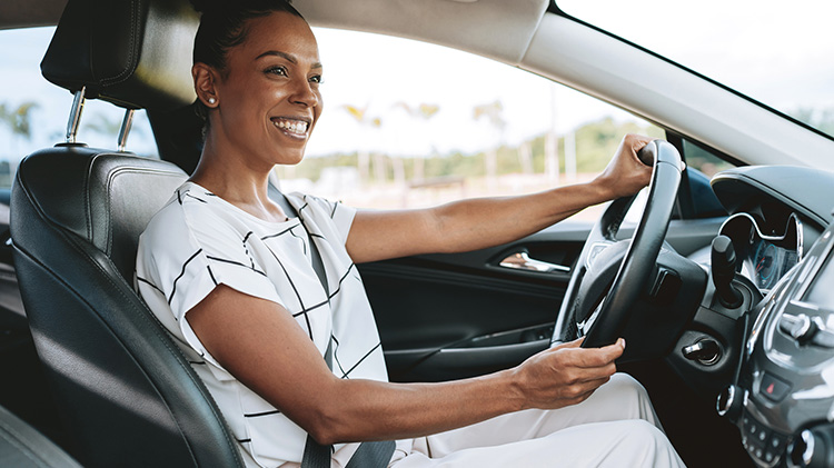 A young adult driver confidently driving her car.