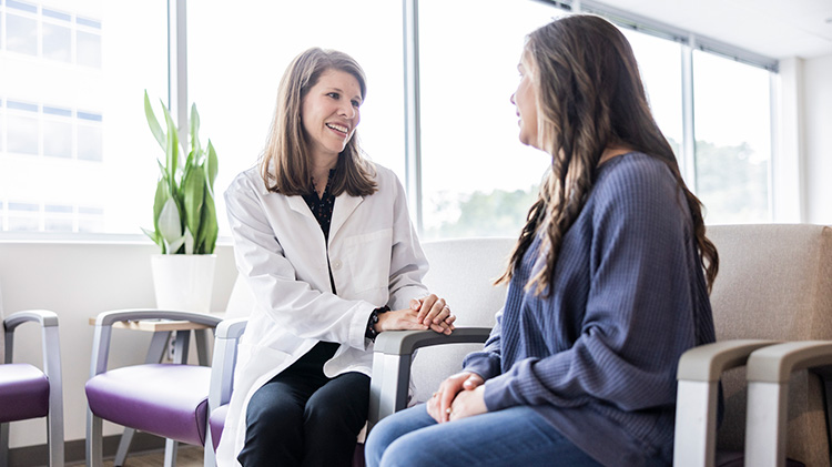 A female doctor checks in with a patient’s family member in the waiting room.