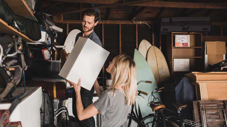 Woman handing man a box in garage for storage.