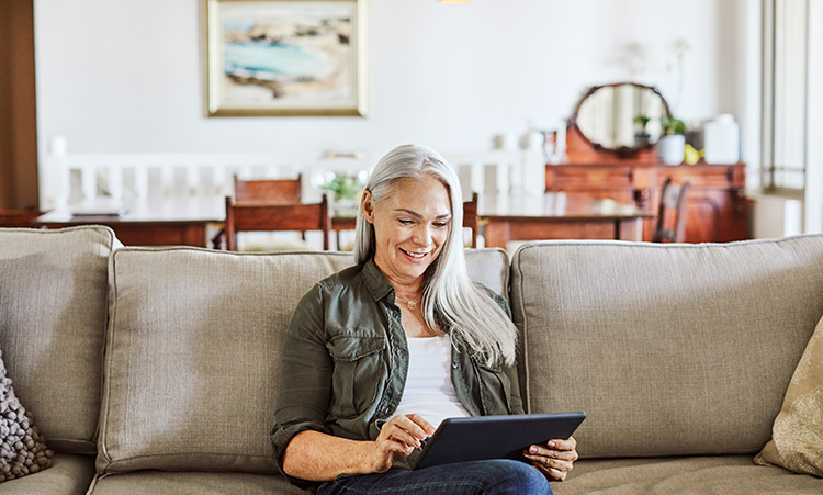 Older Woman Working on Tablet Computer on Couch at Home