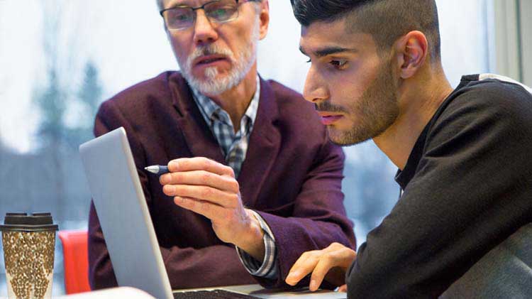 Two men working together at a laptop.