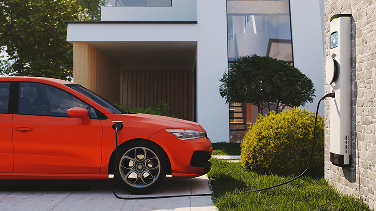 A red electric vehicle plugged into a charging station in front of a modern home.