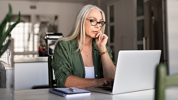 Woman sits in front of laptop, reviewing her estate plan.