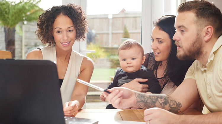 Couple with baby reviewing life insurance with agent.