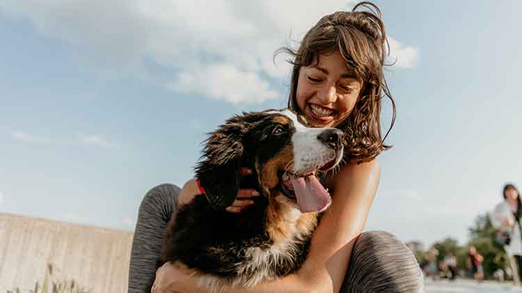 Mujer sonriente con su perro en brazos