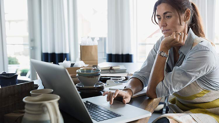 Woman sitting at desk with an open laptop while working from home.