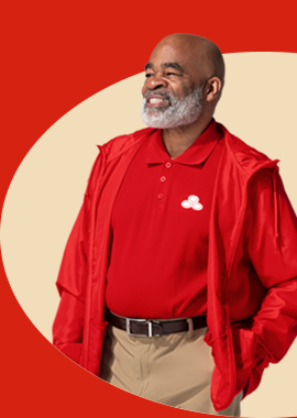 Mature, Black, male agent, bald headed with gray beard; he wears a red polo shirt and red hoodie