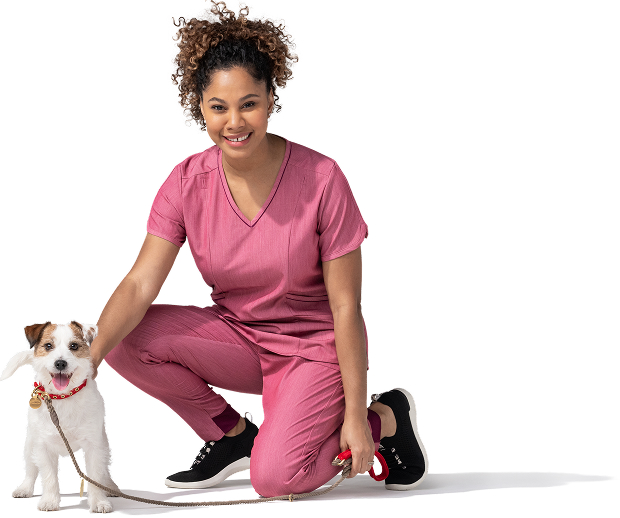 Una joven afroamericana, que es auxiliar de veterinaria, viste un uniforme médico rosa y tenis negros. Tiene sujeto con una correa roja a un jack russell terrier.