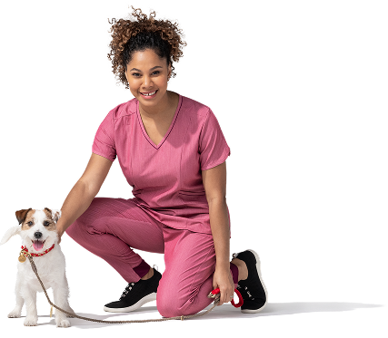 A young, female vet assistant, wearing scrubs, kneels beside a small dog on a leash