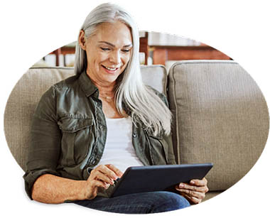 Woman sitting on couch reading her iPad.
