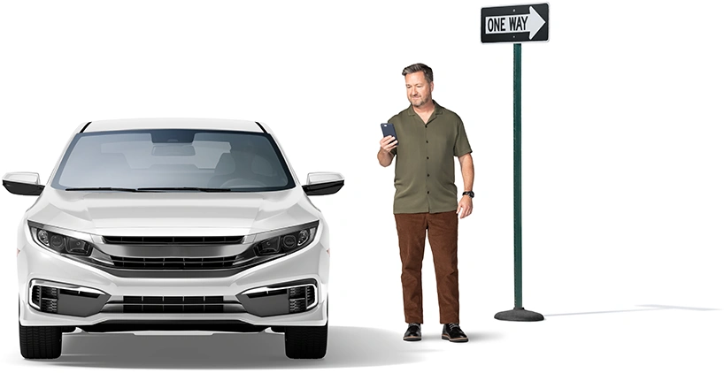 Next to an one-way street marker, man checks his smartphone as his ride arrives.