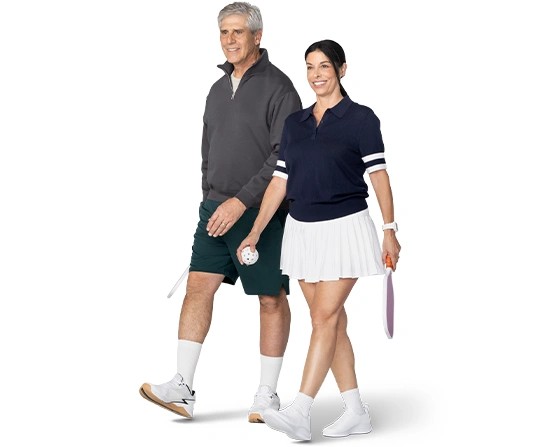 A smiling couple head to the pickeball court.