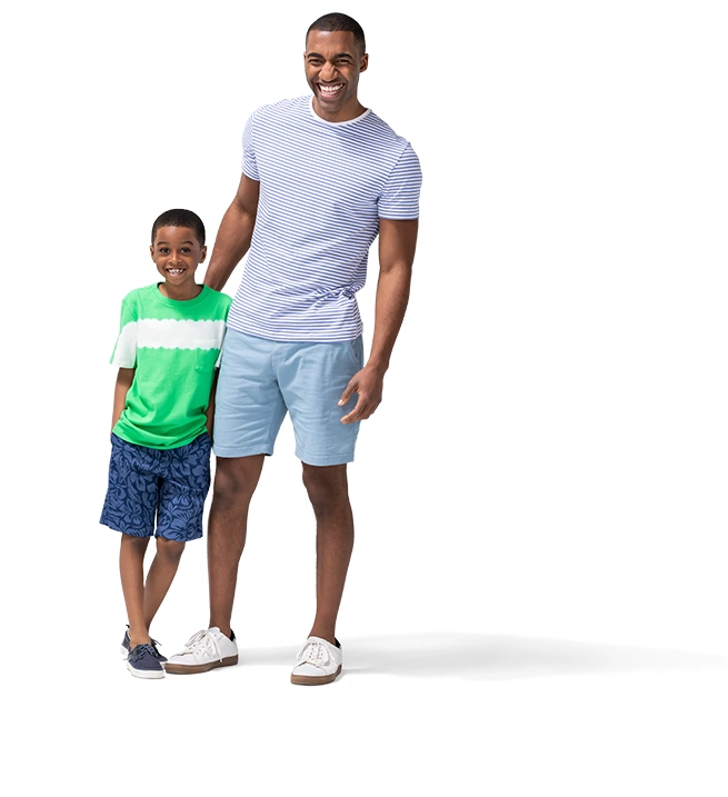 Wearing shorts and tee-shirts, a young boy leans in against his father.