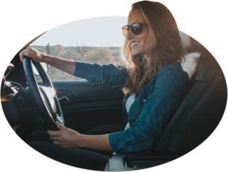 A smiling young woman keeps her eyes on the road.