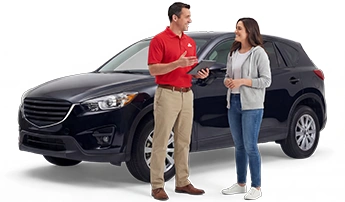 A State Farm agent in a red polo and khaki pants stands next to a customer in a white tee shirt, grey jacket and blue jeans. They are standing in front of a black SUV.