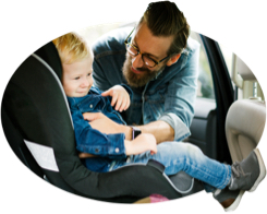 Dad buckles his son into a child safety seat.