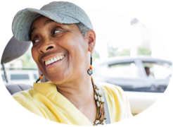 A woman in a ballcap turns and grins at her backseat passenger.