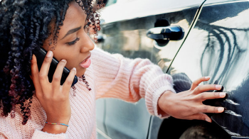 On the phone with a State Farm agent, a woman inspects her car’s exterior.