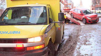 A yellow ambulance parks near a damaged white vehicle.
