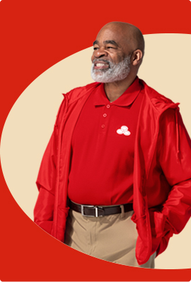 A bearded State Farm agent in red shirt and red pullover jacket smiles.