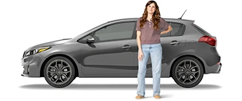 Una joven está parada al lado de su SUV gris con la mano detrás de la espalda. Va vestida con una camisa marrón y jeans azules.